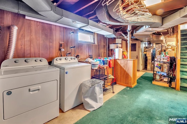 clothes washing area with wooden walls, laundry area, light colored carpet, and washer and clothes dryer