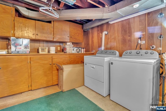 clothes washing area featuring independent washer and dryer and cabinet space