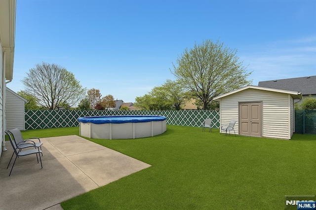 view of yard featuring a storage shed, a fenced in pool, a fenced backyard, an outbuilding, and a patio