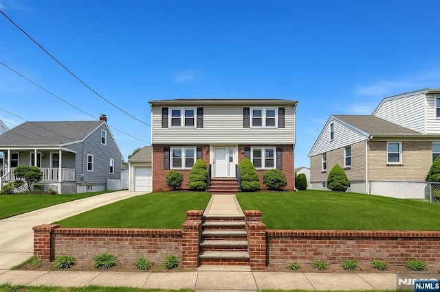 colonial inspired home with brick siding, a garage, a front lawn, and driveway