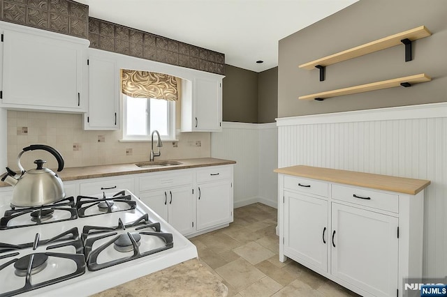 kitchen featuring a sink, open shelves, white cabinets, and range with gas cooktop