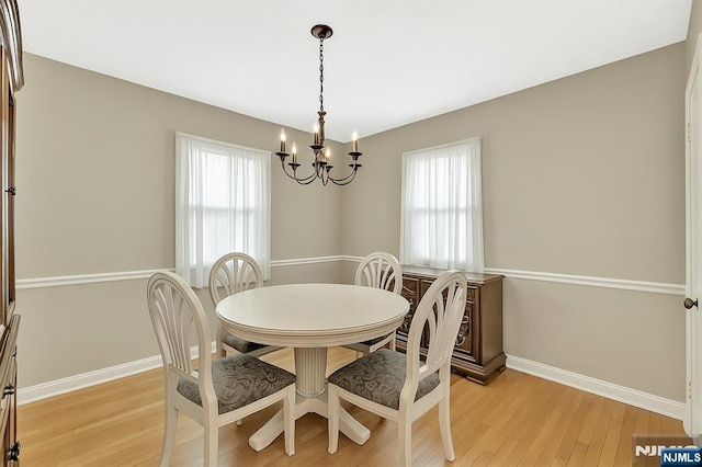 dining space with baseboards, a notable chandelier, a healthy amount of sunlight, and light wood finished floors