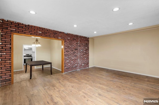 unfurnished room featuring recessed lighting, brick wall, baseboards, and light wood finished floors