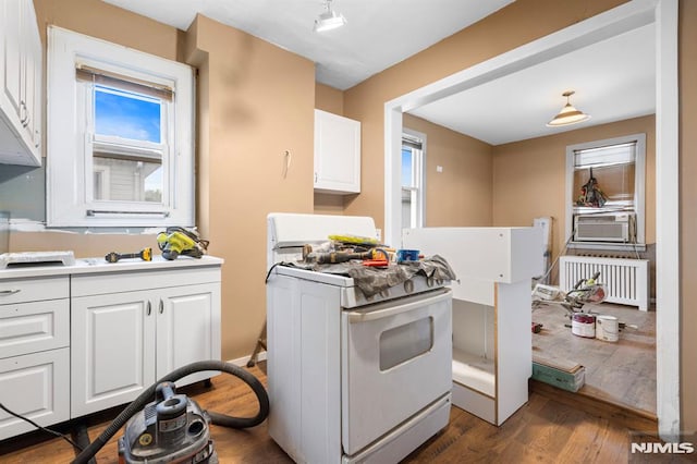 kitchen with radiator, white gas range oven, dark wood-style floors, and white cabinets