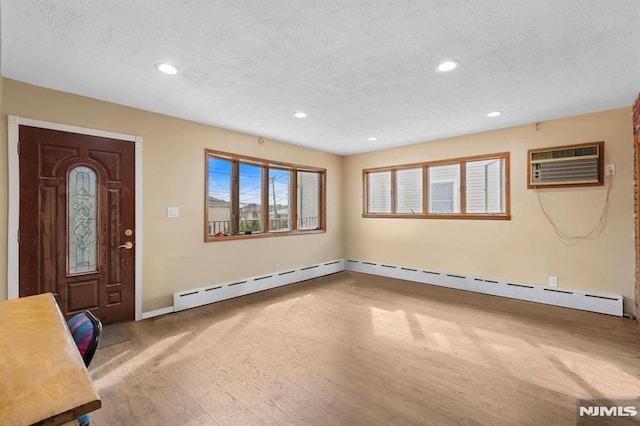 entryway with a wall unit AC, a textured ceiling, baseboards, a baseboard radiator, and recessed lighting