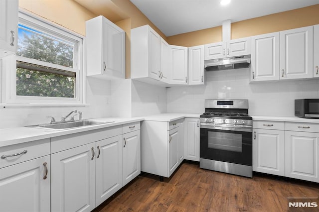 kitchen with under cabinet range hood, white cabinets, tasteful backsplash, stainless steel range with gas stovetop, and a sink