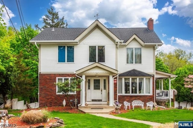 traditional home featuring brick siding, a chimney, and a front yard