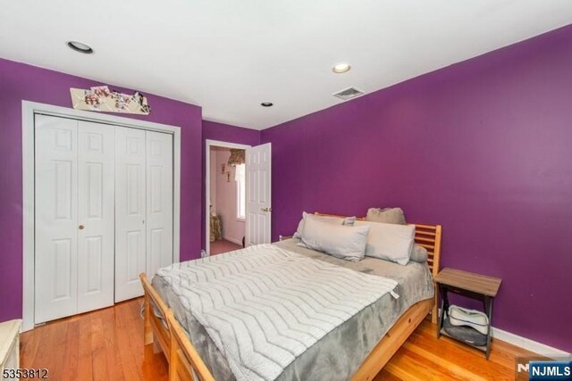 bedroom featuring recessed lighting, baseboards, wood finished floors, visible vents, and a closet