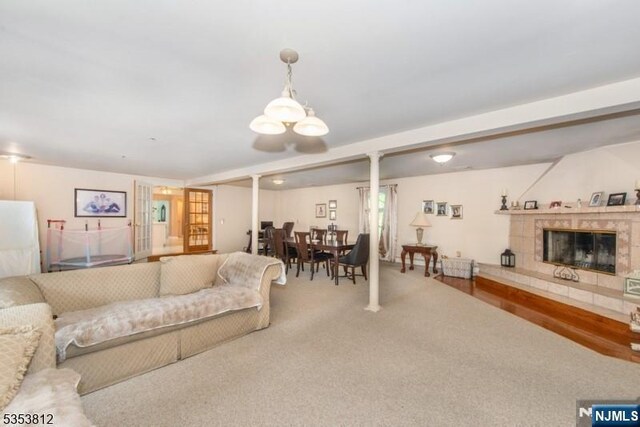 carpeted living area featuring an inviting chandelier and a fireplace
