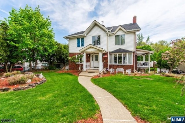 view of front of home with a chimney, a front lawn, and brick siding