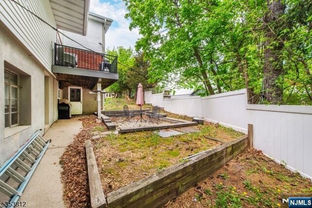 view of yard featuring a balcony, fence, and a vegetable garden