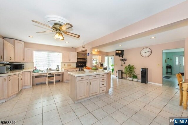 kitchen with light countertops, light tile patterned floors, black microwave, and a wealth of natural light