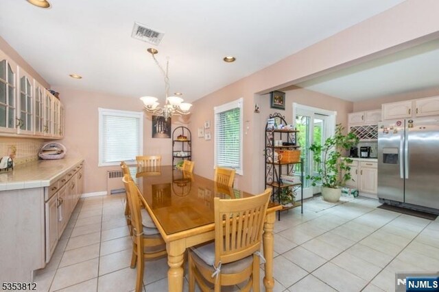 dining room with visible vents, radiator heating unit, recessed lighting, light tile patterned floors, and a notable chandelier