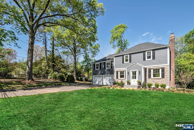 view of front of property with a garage, aphalt driveway, a front yard, and a chimney