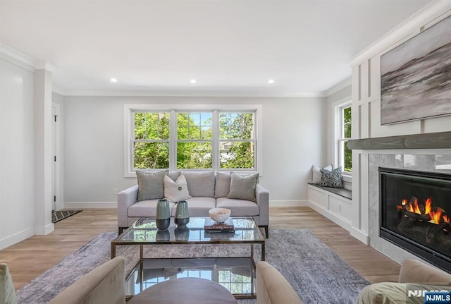living room featuring crown molding, a premium fireplace, baseboards, and recessed lighting