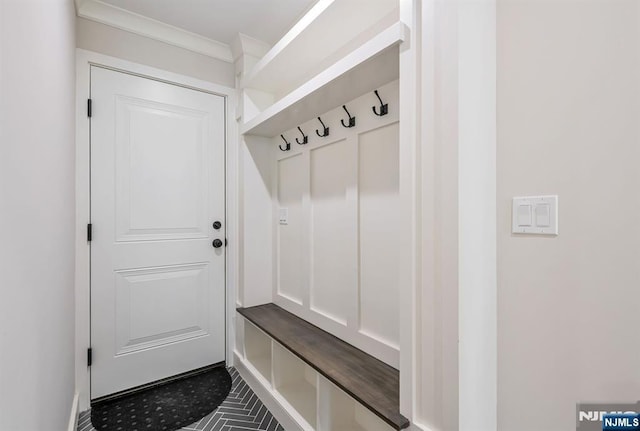 mudroom featuring crown molding and dark tile patterned flooring