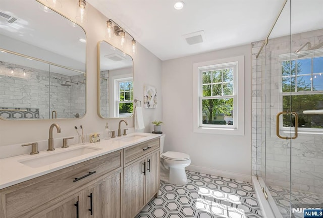 bathroom featuring double vanity, a sink, a stall shower, and toilet