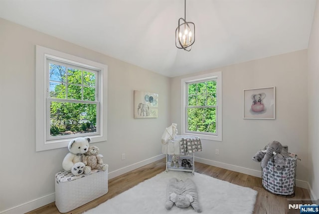 miscellaneous room with baseboards, wood finished floors, and a notable chandelier