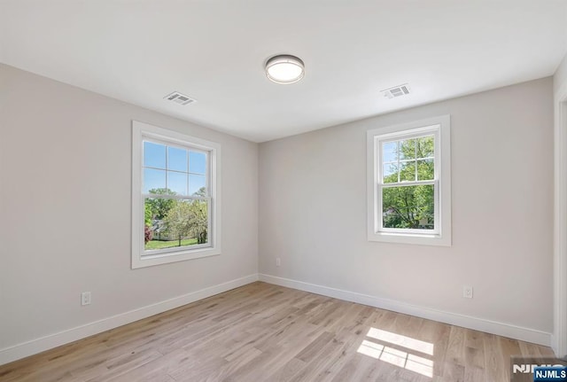 empty room featuring baseboards, light wood-style flooring, and visible vents