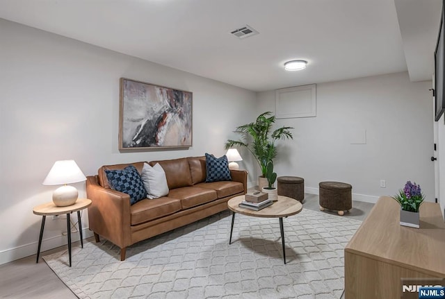 living area with light wood-style floors, baseboards, and visible vents