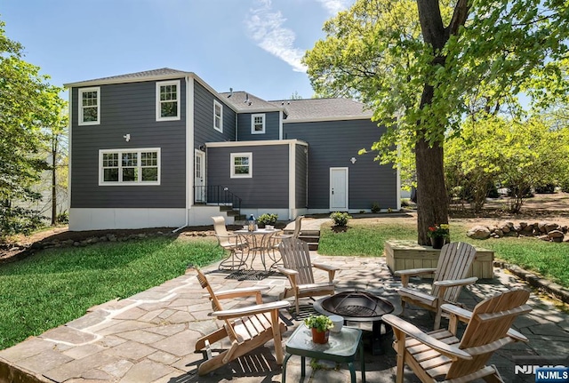 back of house featuring roof with shingles, a patio, a yard, and an outdoor fire pit