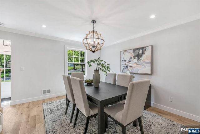 dining area featuring visible vents, ornamental molding, an inviting chandelier, baseboards, and light wood-style flooring