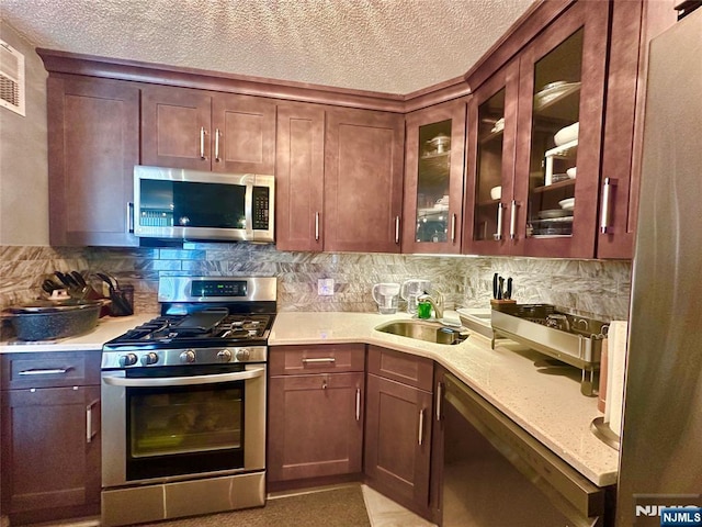 555 N Ave Unit 4C, Fort Lee, NJ 07024 - kitchen featuring a sink, a textured ceiling, stainless steel appliances, tasteful backsplash, and glass insert cabinets