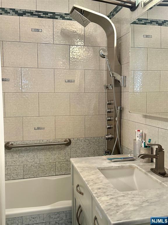555 N Ave Unit 4C, Fort Lee, NJ 07024 - full bathroom featuring vanity, tiled shower / bath combo, and tile walls