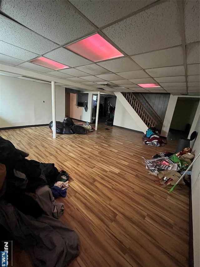 finished basement with a drop ceiling, wood finished floors, and stairway