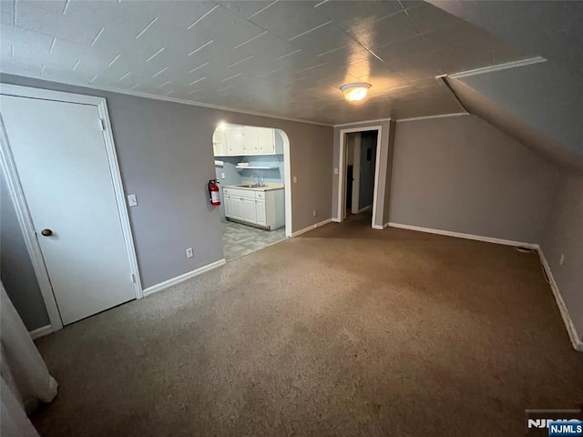bonus room featuring light colored carpet, arched walkways, baseboards, and a sink