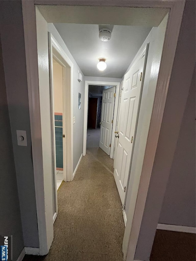 corridor with baseboards and carpet