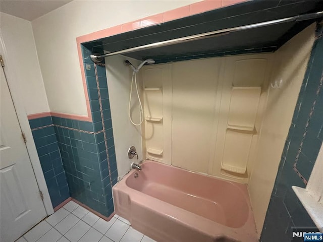 full bath with tile walls, tile patterned flooring, wainscoting, and shower / tub combination