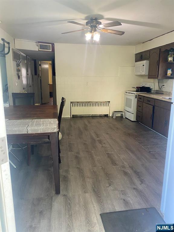 dining space featuring ceiling fan, visible vents, radiator heating unit, and dark wood-type flooring