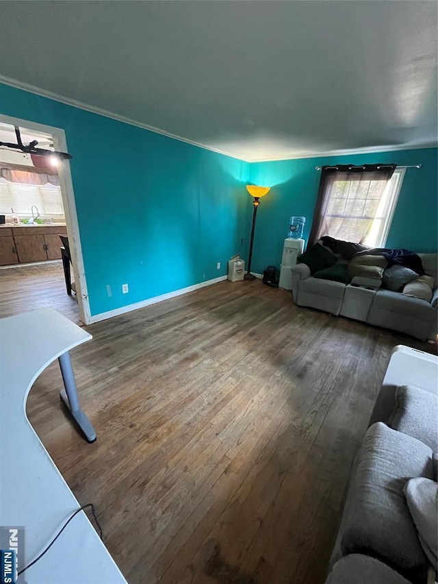 living area with baseboards, ornamental molding, and wood finished floors