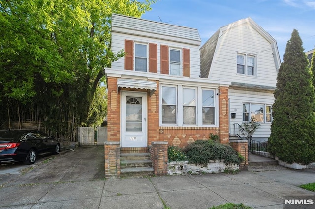 118 W 49th St, Bayonne, NJ 07002 - view of front of property featuring entry steps, fence, a gambrel roof, and brick siding