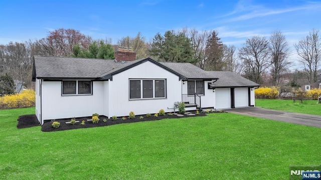 single story home featuring a garage, a front yard, a chimney, a shingled roof, and driveway