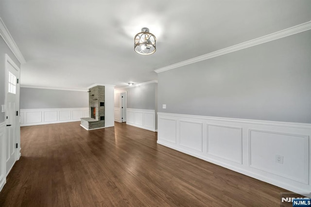 unfurnished dining area featuring a wainscoted wall, ornamental molding, a fireplace, and a decorative wall