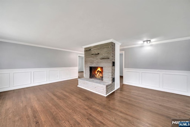 unfurnished living room with a brick fireplace, ornamental molding, and wood finished floors