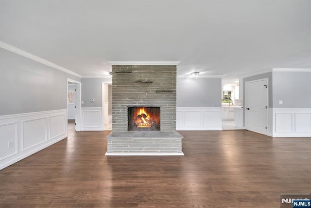 unfurnished living room with crown molding, a decorative wall, wood finished floors, and a fireplace