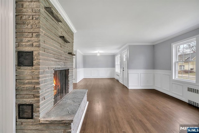 unfurnished living room with a brick fireplace, visible vents, and radiator heating unit