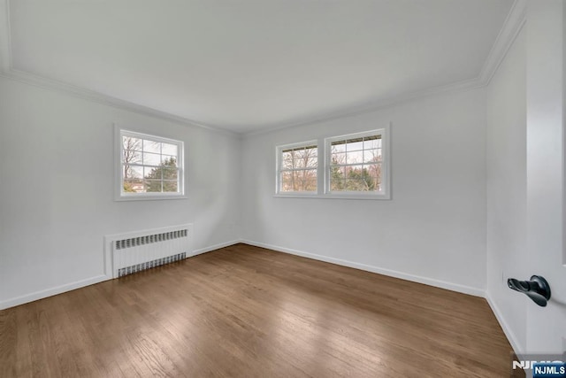 unfurnished room with radiator heating unit, ornamental molding, plenty of natural light, and wood finished floors