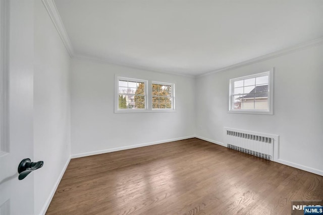 unfurnished room with radiator heating unit, crown molding, wood finished floors, and a healthy amount of sunlight