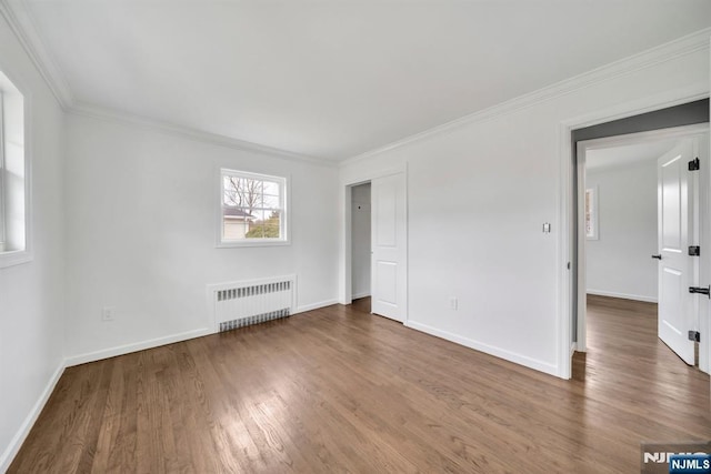 unfurnished bedroom featuring baseboards, ornamental molding, radiator heating unit, and wood finished floors
