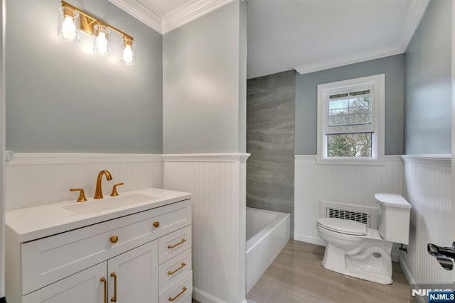 bathroom featuring wainscoting, vanity, toilet, a bathtub, and ornamental molding