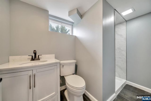 full bathroom with vanity, baseboards, toilet, and tiled shower