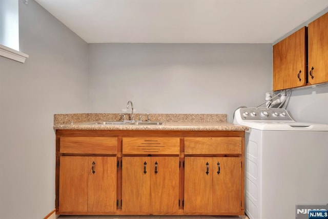 clothes washing area featuring a sink, washer / dryer, and cabinet space