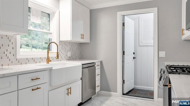 kitchen featuring appliances with stainless steel finishes, a sink, white cabinetry, baseboards, and decorative backsplash