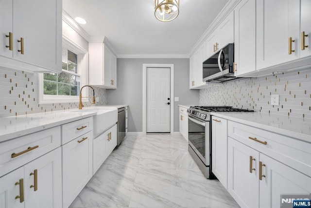 kitchen featuring ornamental molding, decorative backsplash, appliances with stainless steel finishes, and white cabinetry