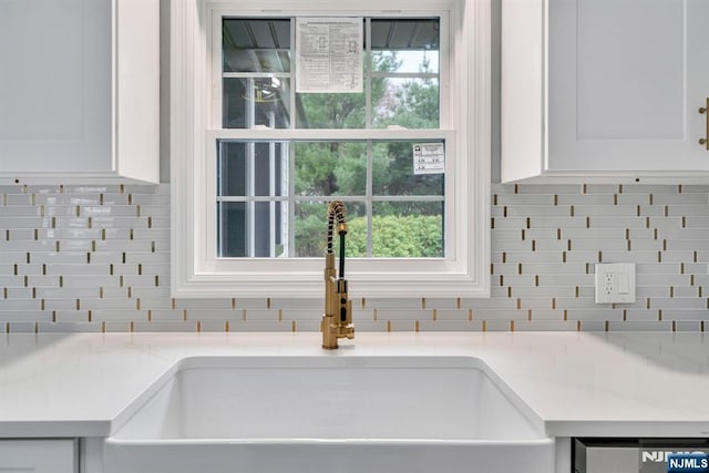 room details with a sink, white cabinetry, backsplash, and dishwasher