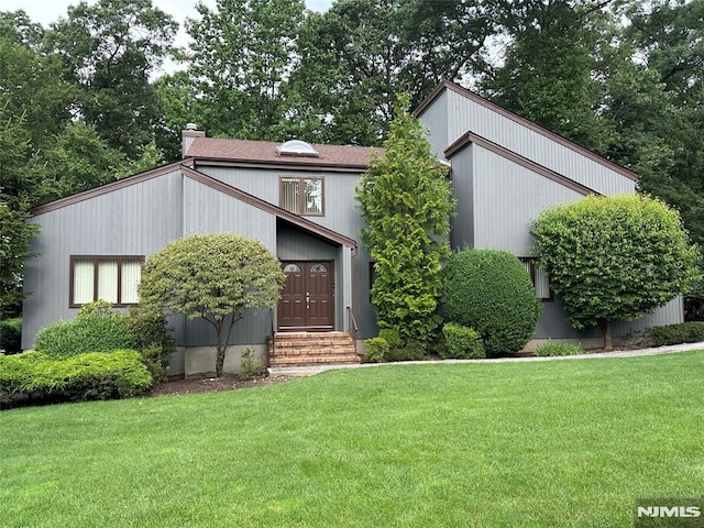 mid-century modern home with a front lawn and a chimney